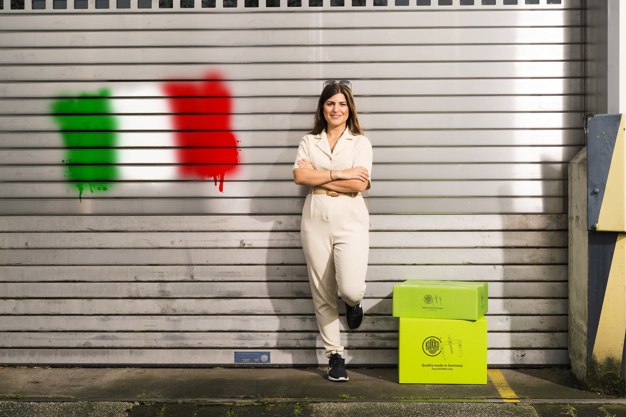 K+K ITALIA Mitarbeiterin vor Rolltor mit italienischer Flagge
